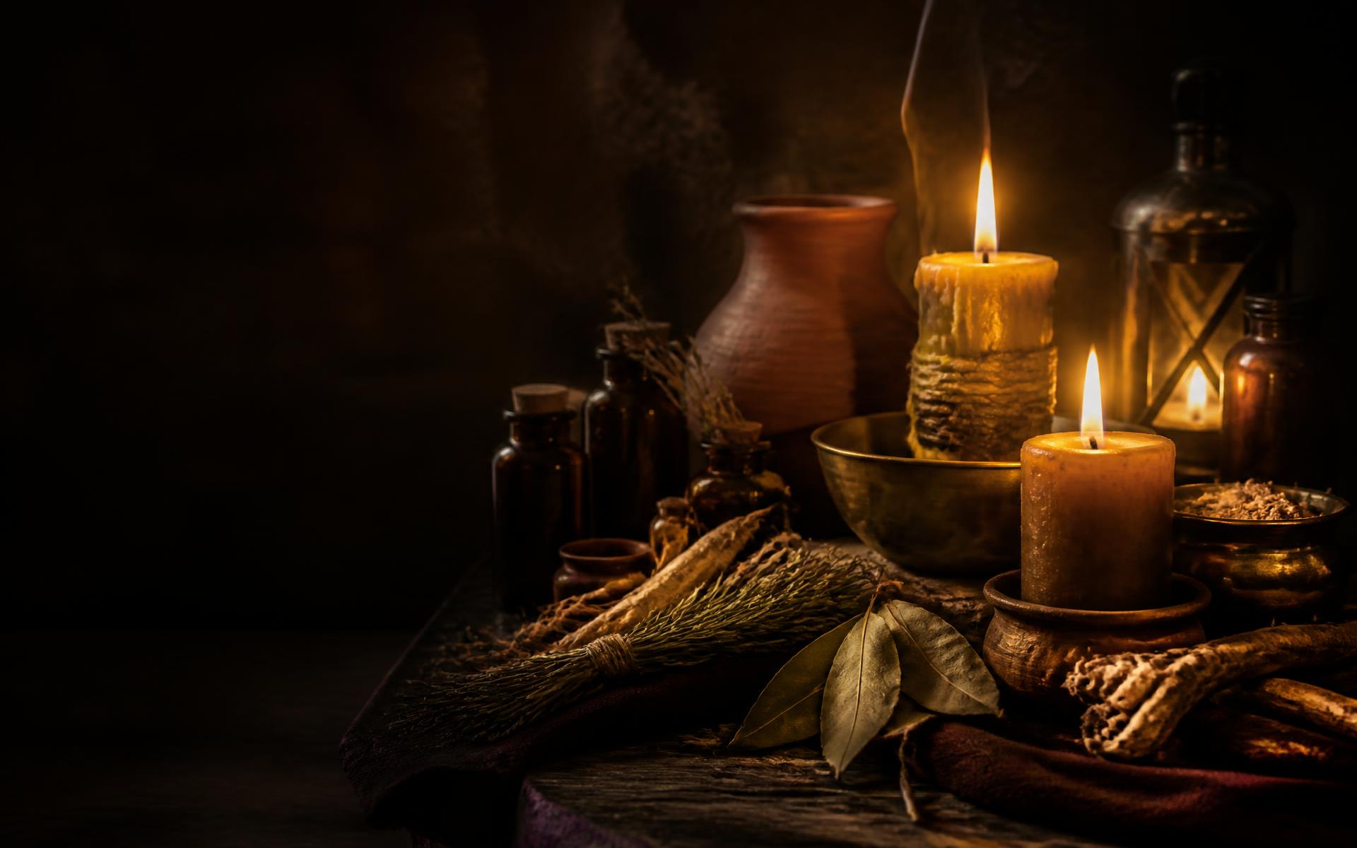 Handmade candles, roots, herbs, and amber apothecary bottles arranged in warm light